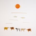 Das Schäfchen-Mobile: 5 Schäfchen in rot-gelb Tönen hängen unter der Sonne und zwei Wölkchen