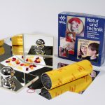 Die Experimentiermaterialien mit vielen verschiedenen Spiegeln liegen rund um die Experimentierschachtel Spiegelspiele