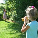 Zwei Mädchen telefonieren mit dem Schnurtelefon im Garten.