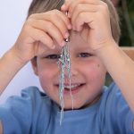 Ein Junge schaut hinter den vom Magneten angezogenen Nägeln.