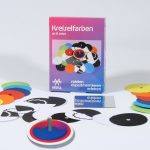 Die Kreiselscheiben liegen rund um die Experimentierschachtel Kreiselfarben
