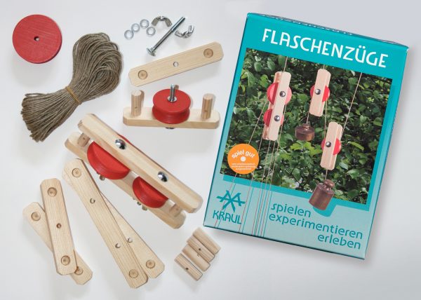 Die hölzernen Teile für den Bau eines Flaschenzugs liegen um die Experimentierschachtel Flaschenzüge