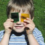 ein Junge schaut durch eine grüne und eine gelbe Folie vom Der Kleine Farbenspaß