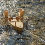 Das Boot Forelle paddelt an einer Schnur in einem kleinen Fluss