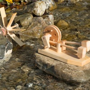 Von einem kleinen Wasserrad angetrieben hämmert das Hammerwerk auf einem Flussstein stehend.