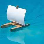 Das kleine Segelschiff Kári aus Holz durchquert mit Bugwelle einen Pool.