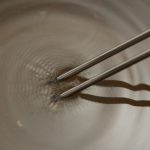 Eine Stimmgabel versetzt Wasser in Schwingung. Ein Versuch aus dem Experimentierkasten Horchkiste