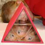 Ein Kind schaut durchs Große Kaleidoskop und wird bizarr widergespiegelt