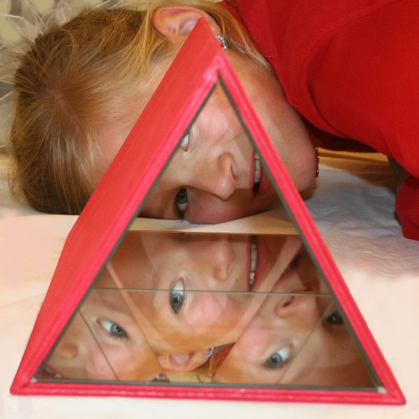 Ein Kind schaut durchs Große Kaleidoskop und wird bizarr widergespiegelt