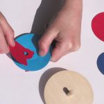 Ein Kind steckt die Kreiselscheiben des Experimentierkastens Kreiselfarben zusammen.