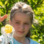 Ein Mädchen lässt einen Ball auf einem Wasserstrahl tanzen, Versuch aus dem Experimentierkasten Wirbel in Wasser und Luft